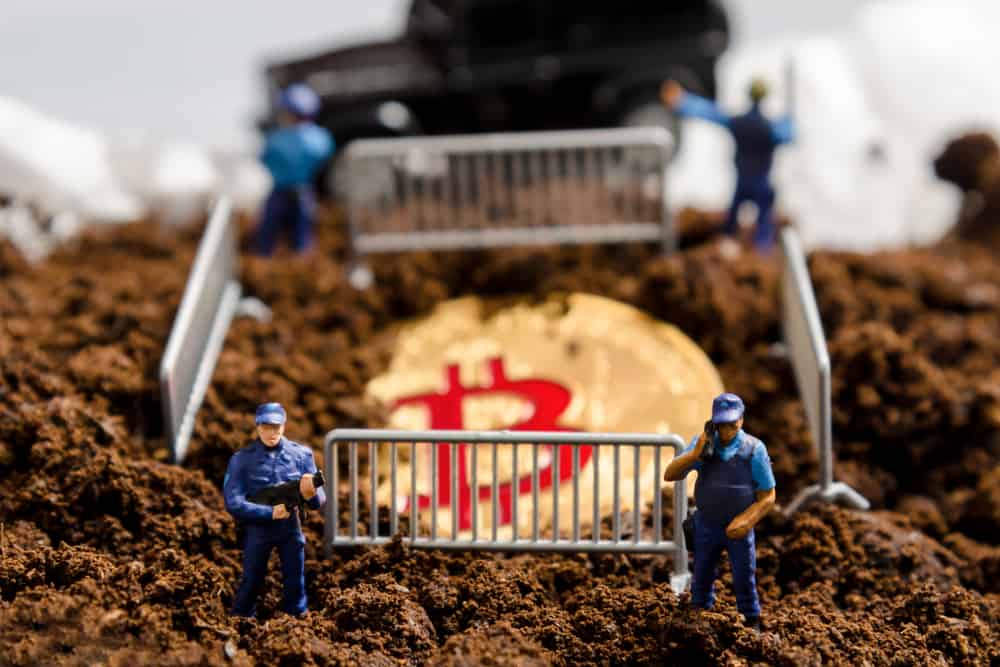 miniature policeman officers stand watch over bitcoin in fence. digital virtual cryptocurrency money blockchain concept. Sources: shutterstock.com