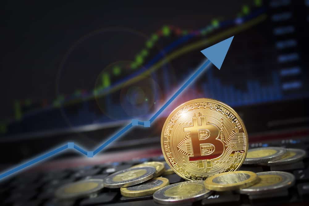 Bitcoin currency rising arrow price record highs on keyboard computer with golden bitcoin and other currencies. Source: shutterstock.com