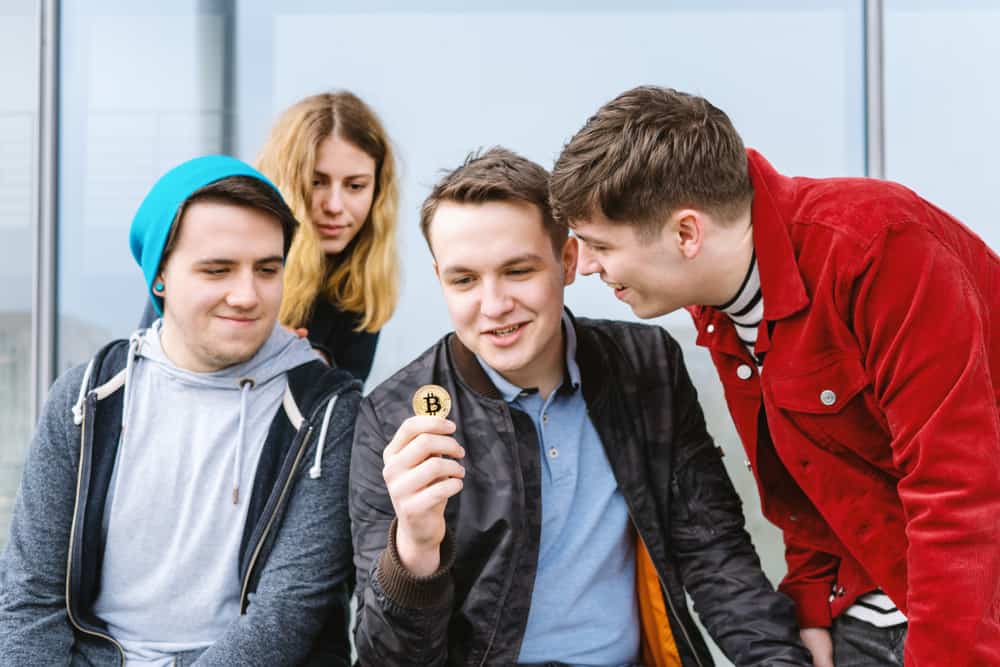 Young man showing crypto token to friends