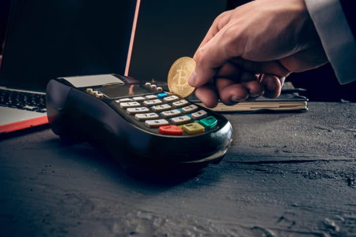 Bitcoin, credit card and POS-terminal. The golden bitcoin in male hands. Cryptocurrency bitcoin coins. Litecoin, Bitcoin, Ethereum, e-commerce, busibess, finance concept. crypto currency symbol. Source: shutterstock.com